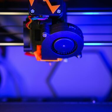 A 3D printer illuminated with neon lights crafting vibrant orange models.