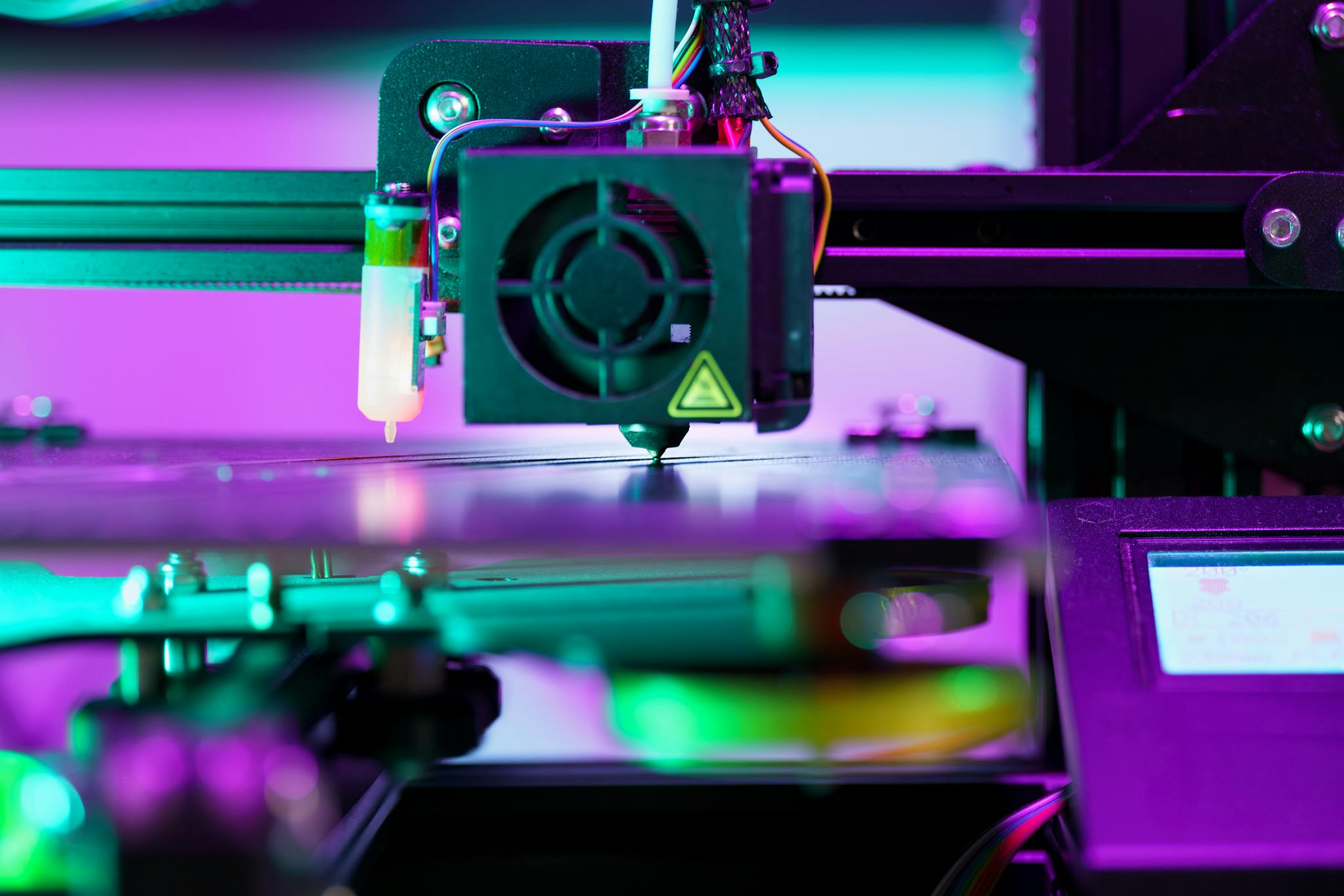 A neon-lit 3D printer operating, showcasing advanced technology and engineering.